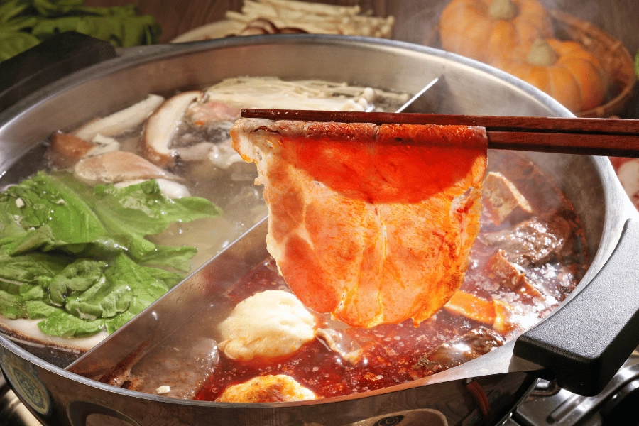 Cooking meat with chop sticks in a hot pot 